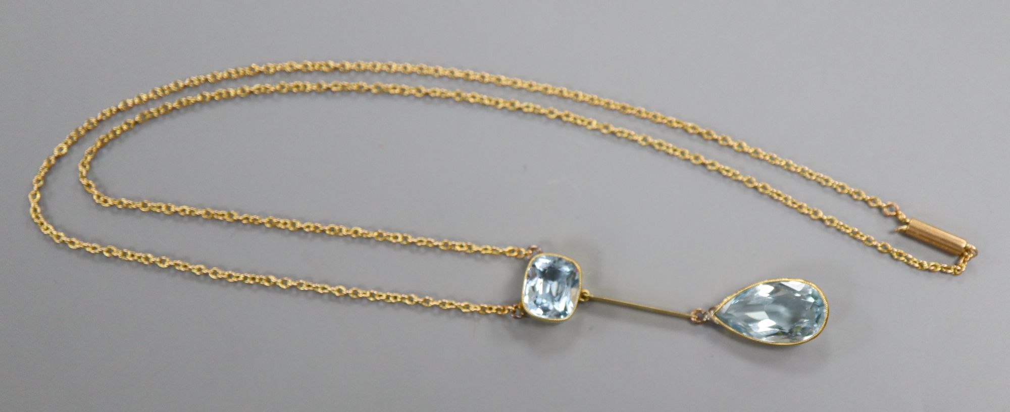 A yellow metal and two stone aquamarine drop pendant necklace, 25.5cm, gross 5.8 grams.